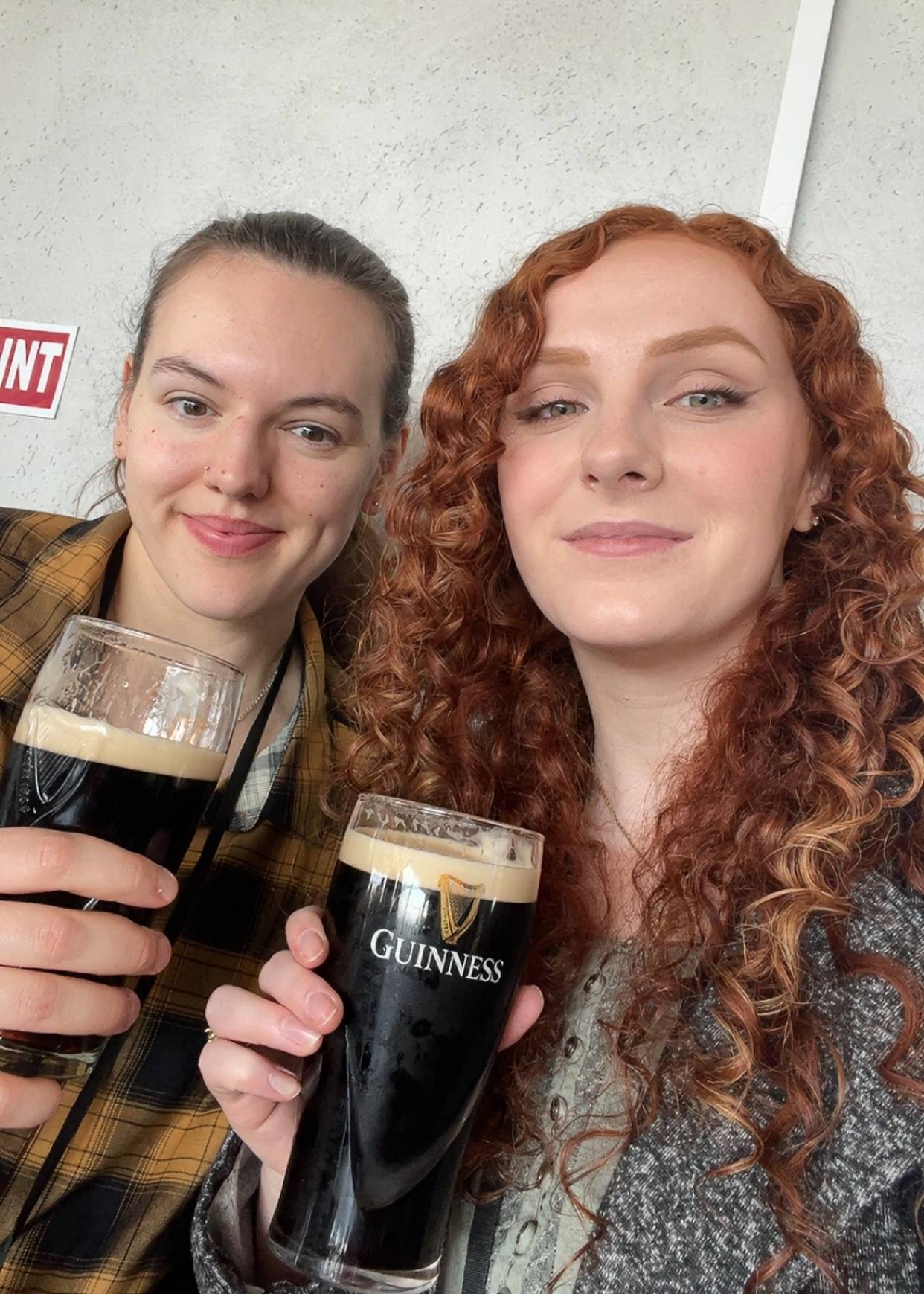 Two alumni pose with glasses of Guinness